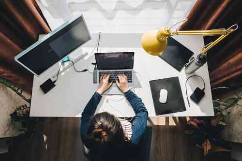 Frau sitzt im Homeoffice beim Schreibtisch und arbeitet am Laptop
